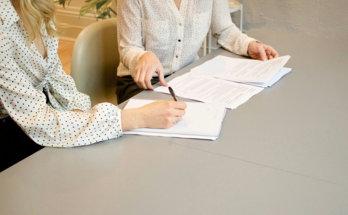 woman-signing-on-white-printer-paper-beside-woman-about-to-touch-the-documents.jpg woman signing on white printer paper beside woman about to touch the documents